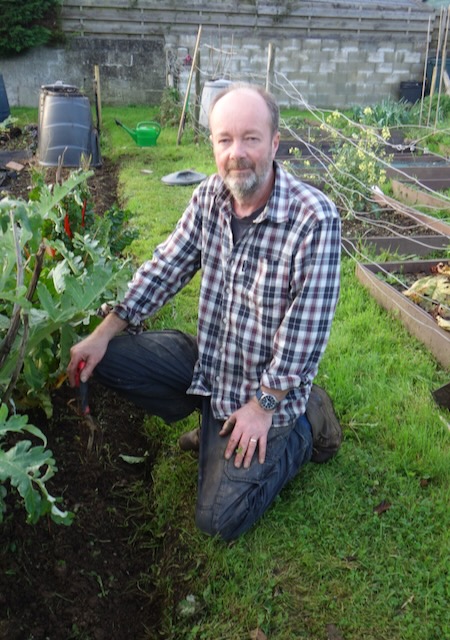 John kneeling beside vegetables on the allotment